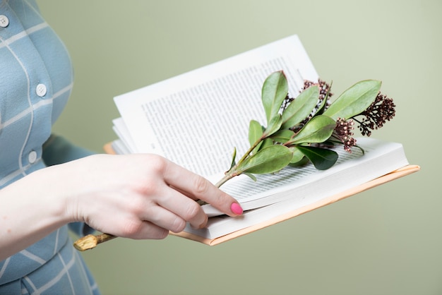 Primer plano de manos con libro y adorno floral