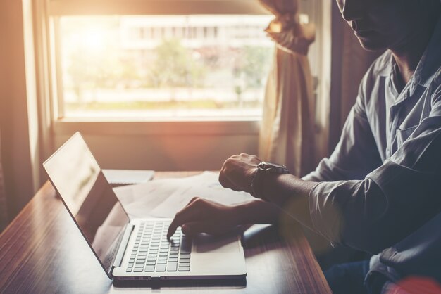 Primer plano de las manos masculinas que usan la computadora portátil en casa.