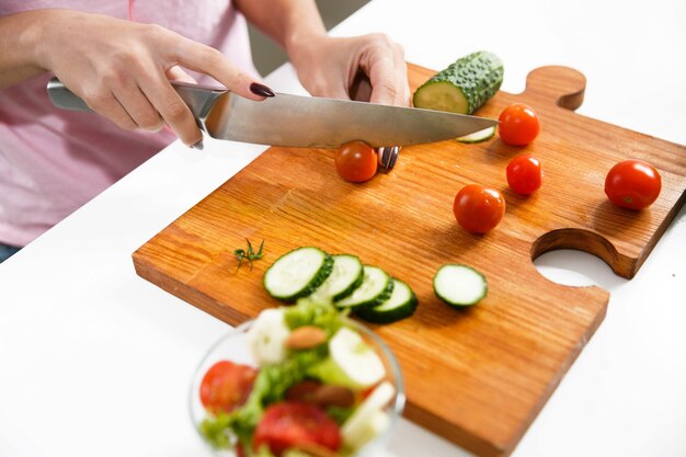 Primer plano de manos de mujer cortar tomates en el tablero de madera