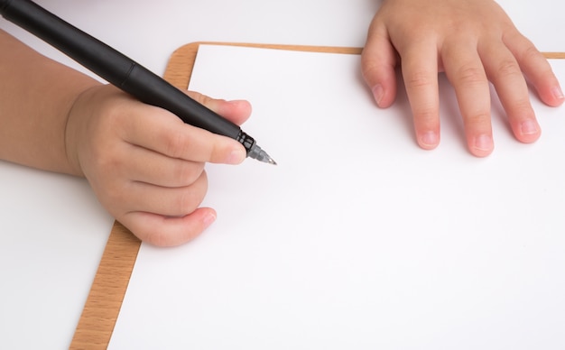 Primer plano de las manos de un niño dibujando en un papel en blanco 