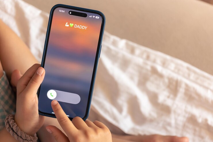 Foto gratuito primer plano de las manos de un niño sosteniendo el teléfono con una llamada entrante de papá en la pantalla