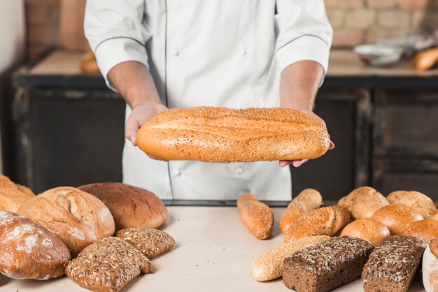 Primer plano de las manos de panadero masculino con pan fresco