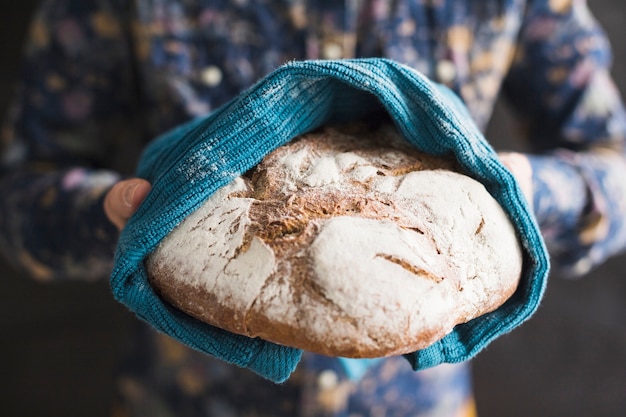 Primer plano de manos sosteniendo pan horneado envuelto en servilleta azul