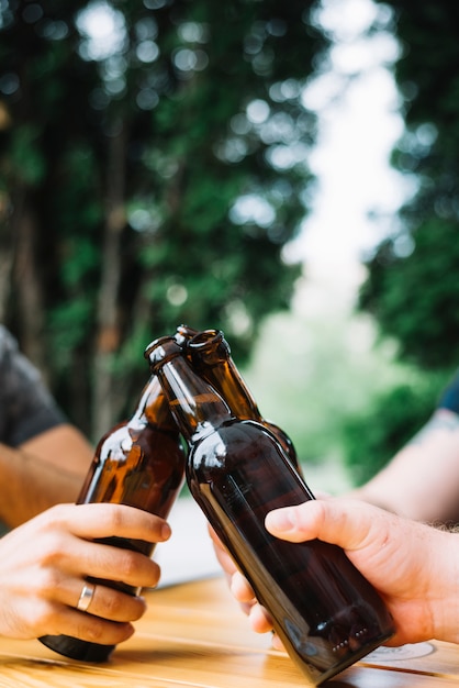 Primer plano de manos tintineando las botellas de cerveza sobre la mesa