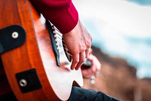 Foto gratuita primer plano de manos tocando la guitarra acústica