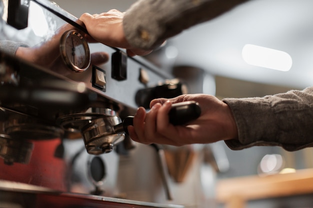 Primer plano de manos trabajando en la máquina de café