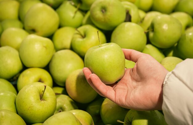 Primer plano una manzana en la mano de una mujer una selección de frutas en un supermercado