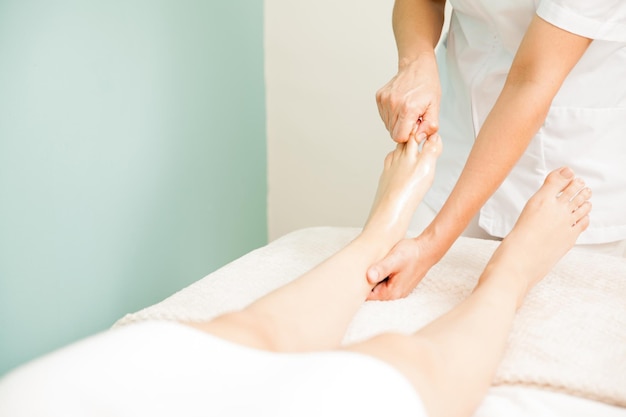 Primer plano de una masajista dando un masaje de pies a un cliente en un spa. Mucho espacio de copia