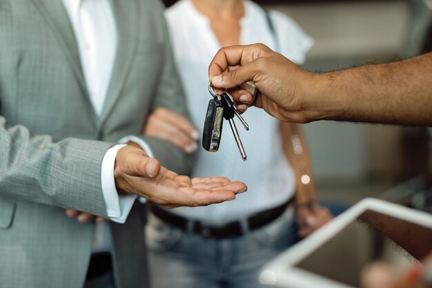 Primer plano de mecánico dando llaves de coche a su cliente en un taller