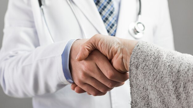 Primer plano de un médico masculino y un paciente estrechándose las manos