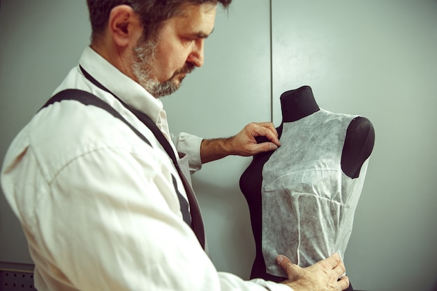 Foto gratuita primer plano de la mesa de sastres con manos masculinas trazando patrón de fabricación de tela para ropa en el estudio de taller tradicional. el hombre de profesión femenina. concepto de igualdad de género