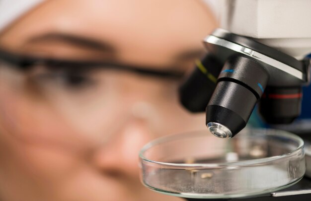 Primer plano del microscopio en el laboratorio con mujer científico