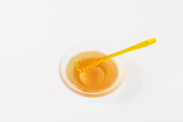 Primer plano de miel dulce con cazo sobre fondo blanco