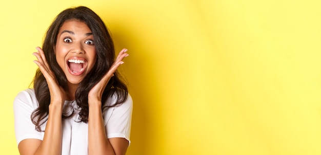 Foto gratuita primer plano de una modelo femenina afroamericana emocionada jadeando y mirando asombrada levantando las manos y sein