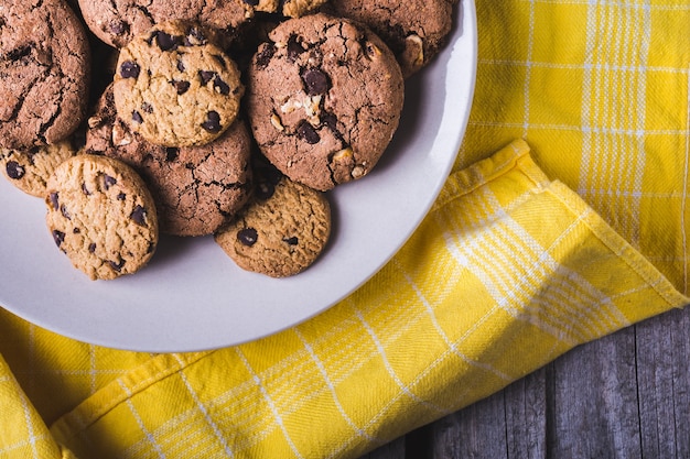 Primer plano de un montón de galletas con chispas de chocolate en una placa blanca.