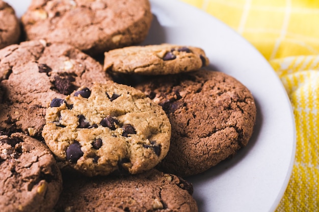 Primer plano de un montón de galletas con chispas de chocolate en una placa blanca.