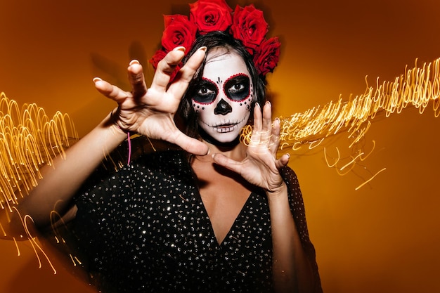 Foto gratuita primer plano de una morena con una corona de rosas rojas dama vestida de no halloween posa para un retrato