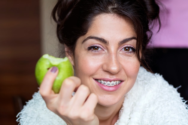 Primer plano de mujer alegre comiéndo una manzana