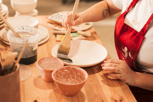 Primer plano de mujer artesana pintando el plato con pincel