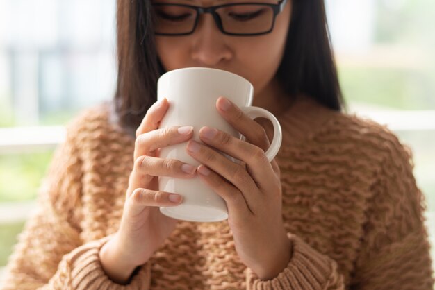 Primer plano de mujer asiática bebiendo café caliente de taza