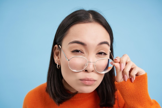 Foto gratuita primer plano de mujer asiática en gafas pensando mirando a la cámara con expresión de cara pensativa standi