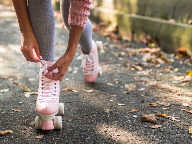 Primer plano de mujer atar cordones de los zapatos en patines con hojas