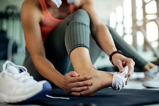 El primer plano de una mujer atlética se lastimó el pie durante el entrenamiento en el gimnasio