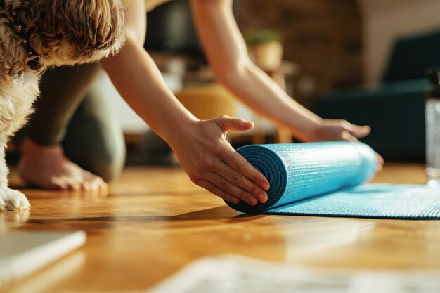 El primer plano de una mujer atlética preparándose para el entrenamiento deportivo y desenrollando su colchoneta de ejercicios en el suelo