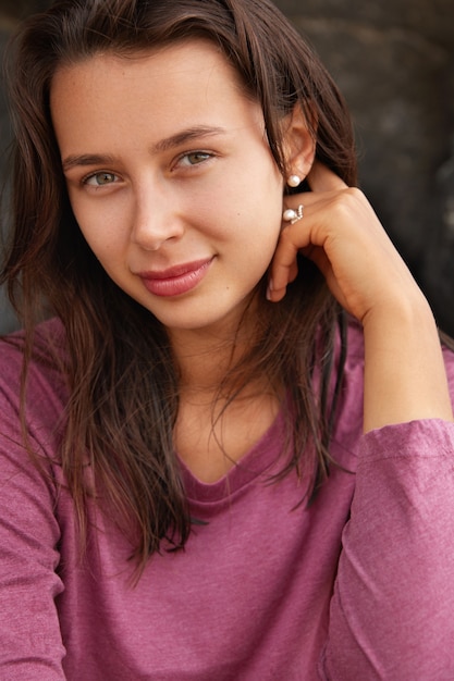 Primer plano de mujer atractiva con cabello oscuro, ojos verdes, labios grandes, mira directamente