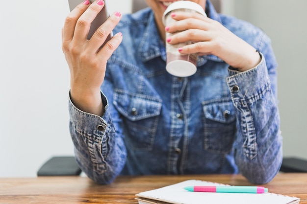 Primer plano de mujer con bebida y teléfono móvil