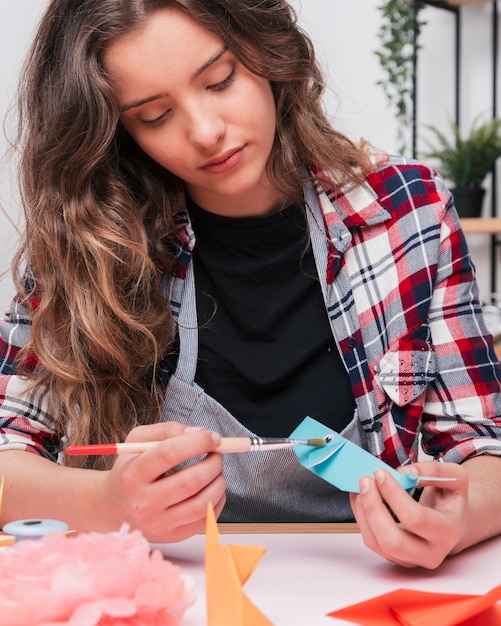 Foto gratuita primer plano de mujer bonita pintando un pez de papel de origami