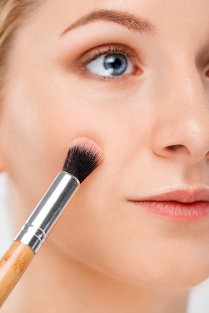 Primer plano de mujer bonita poner maquillaje con pincel