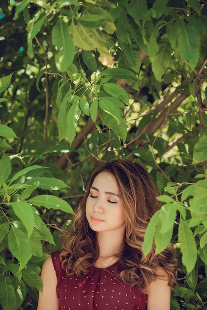 Primer plano de mujer en el bosque disfrutando de la naturaleza con los ojos cerrados