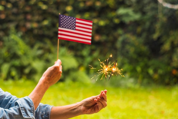 Primer plano de mujer celebrando el día de la independencia con bandera de Estados Unidos y chispas de fuego