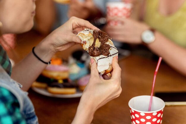 Primer plano de mujer comiendo donut de chocolate glaseado