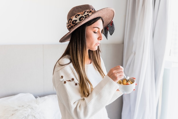 Primer plano de mujer comiendo la ensalada de frutas en el tazón de fuente blanco