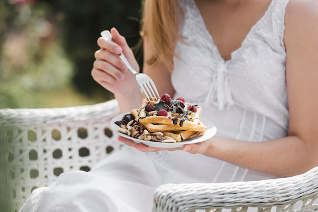 Primer plano de una mujer comiendo gofres en el desayuno