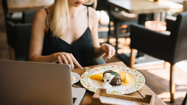 Primer plano de mujer comiendo postre con tenedor y cuchillo de mantequilla