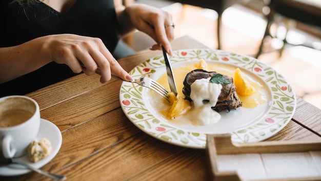 Primer plano de mujer comiendo postre con tenedor y cuchillo de mantequilla