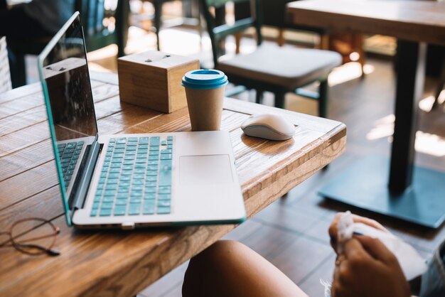 Primer plano de mujer con la computadora portátil en la mesa en el restaurante