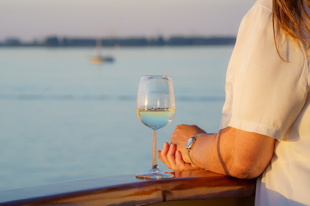 Primer plano de una mujer con una copa de vino en la cubierta de un barco