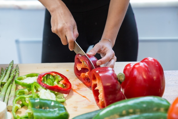 Primer plano de mujer cortando pimiento dulce