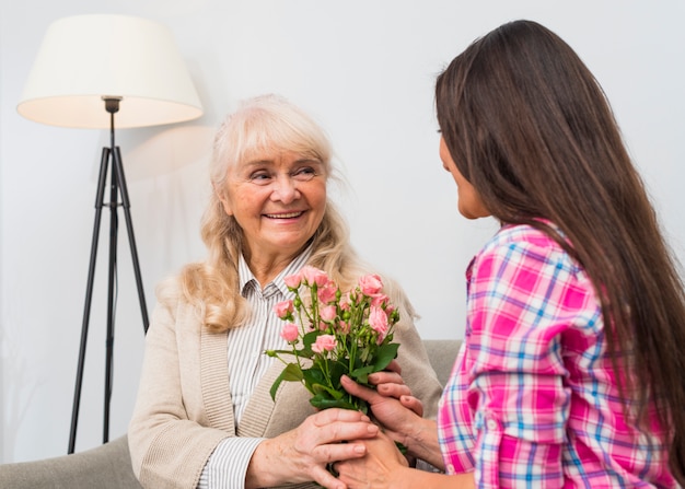 Primer plano de mujer dando flores rosas ramo de flores a su madre senior