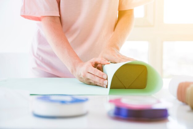 Primer plano de una mujer decorando la caja de regalo con papel decorativo en la mesa