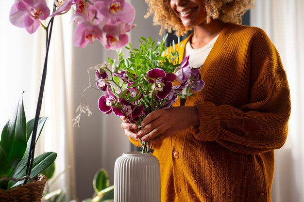 Foto gratuita primer plano de una mujer decorando su casa con orquídeas