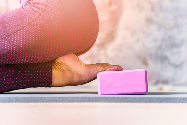 Foto gratuita primer plano de mujer deportiva practicando yoga usando bloque rosa