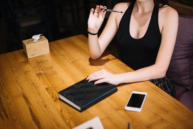 Primer plano de una mujer con diario y teléfono celular en la mesa en el restaurante