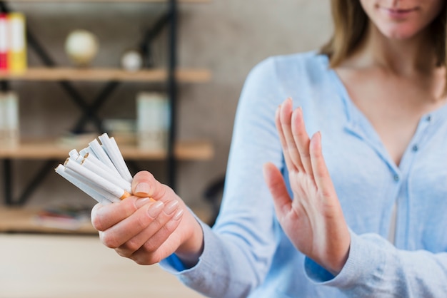 Primer plano de mujer diciendo que no sostiene manojo de cigarrillos en la mano