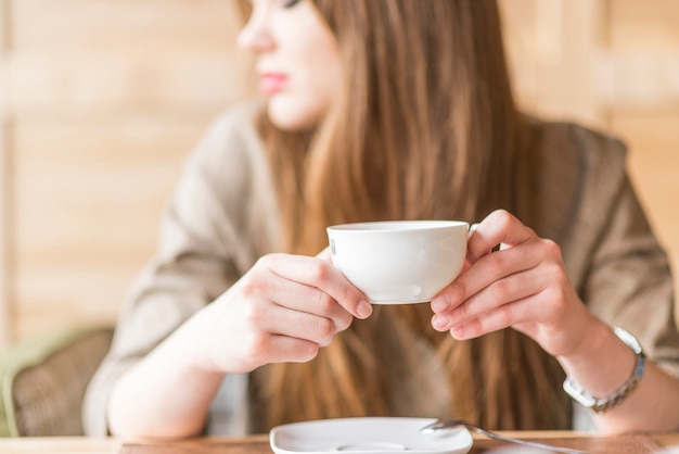 Primer plano de mujer distraída con taza de té