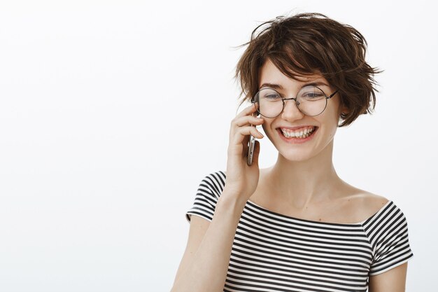 Primer plano de mujer elegante hipster en gafas hablando por teléfono móvil y riendo